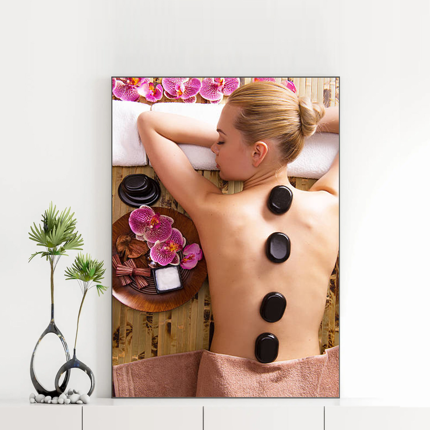Mẫu tranh spa đẹp khổ đứng hình ảnh cô gái nằm thư giãn chườm đá nóng trên lưng, với hoa lan tím và tinh dầu xung quanh