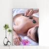 Mẫu tranh spa đẹp chườm đá nóng trên lưng cho cô gái nằm thư giãn với bông hoa lan tím bên cạnh