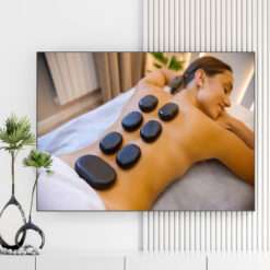 Mẫu tranh spa đẹp hình ảnh nữ khách hàng nằm thư giãn với những viên đá cuội nóng chườm trên lưng